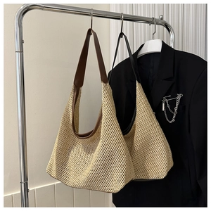 Detail of woven straw tote bags with contrast leather straps hanging on a metal rack