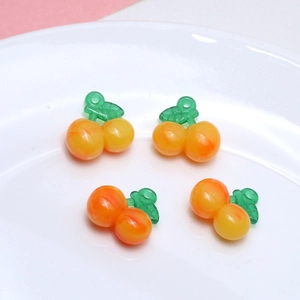 Detailed view of glossy resin cherry charms in orange and yellow for DIY jewelry making