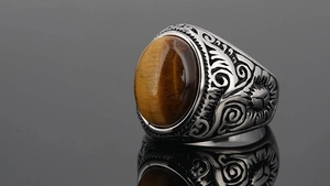 Macro detail of retro stainless steel ring featuring oval tiger eye stone and sun carvings