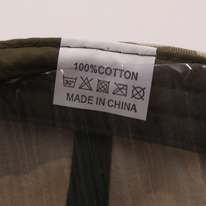 Detail view of cotton washing label inside the camo baseball cap showing 100% cotton fabric