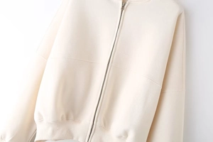 Detail of cream zip-up bomber jacket showing metal zipper and ribbed hem texture