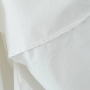 Close-up of fine overlock stitching on lightweight white fabric of a French ballet style dress