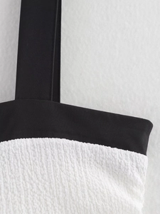 Detailed view of black straps and white textured bubble fabric of a babydoll dress