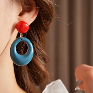 Macro detail of model wearing vintage resin geometric earrings in red and blue colors