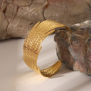Détail macro de la texture de plume dorée sur le bracelet ouvert en acier titane
