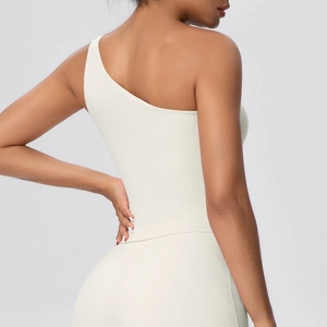 Detail of single-shoulder yoga top showing cream matte fabric and ergonomic seams