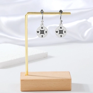 Detailed view of silver compass earrings with NESW letters on polished stainless steel