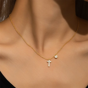 Detail of gold flower cross necklace with sparkling diamonds on a female model
