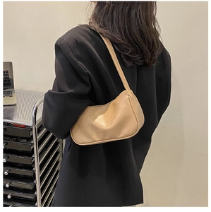 Close-up of khaki minimalist leather underarm bag on model in black suit