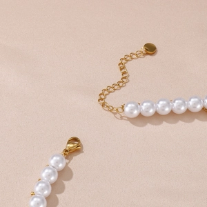 Close-up of golden lobster clasp and extension chain on double-layered pearl necklace