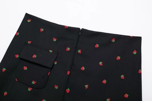 Détail d'une mini-jupe noire avec broderie fraise, fermeture éclair et poche à rabat