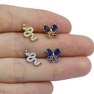 Detail shot showing the tiny scale of a zircon-inlaid snake stud earring on a finger