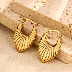 Artistic close-up of gold shell texture earrings on a natural stone base