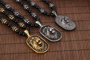 Detail of lion head pendants in gold, silver, and gunmetal on black beaded chains