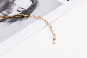 Detailed view of a gold rectangular link chain bracelet placed on a fashion magazine