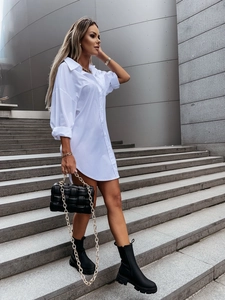 Detail of white button-up shirt dress with lapel collar worn by a model on stone steps
