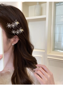 Detail view of two sparkling star hair clips with white rhinestones on dark brown hair