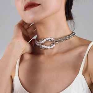 Detail of a knotted choker necklace featuring white pearls and silver metal beads