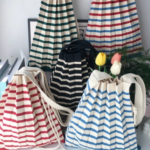 Detailed knit texture and vibrant striped patterns of colorful pleated shoulder bags