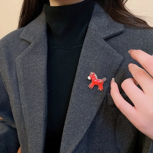 Detail of red enamel horse brooch with gold trim worn on a dark grey blazer lapel