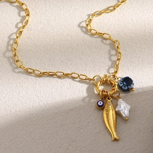 Detail of 18K gold-plated necklace with fish, evil eye, blue flower and pearl charms