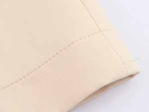 Macro detail of beige woven suit fabric showing fine texture and hem stitching quality