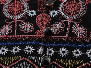 Détail de broderie ethnique et boutons métalliques sur une robe longue noire