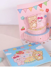 3D pop-up birthday card detail with cute bears and a multi-layer pink and blue cake design