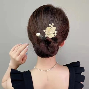 Détail d'un pic à cheveux doré avec papillon en zircon et perle sur chignon bas