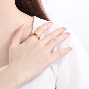 Close-up of a faceted gold titanium steel ring worn on a finger for a minimalist look