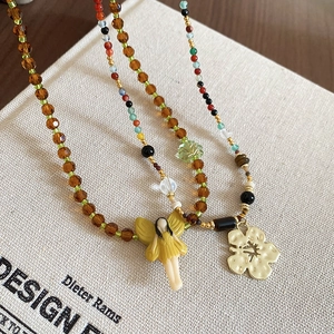 Close-up of resin crystal beaded necklaces with fairy and flower pendants in soft light