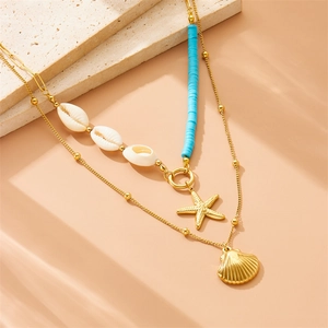 Double-layered gold necklace with starfish, seashell pendants and blue beads on stone surface