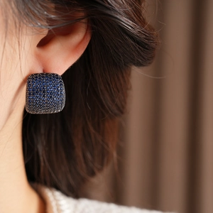 Nahaufnahme der quadratischen blauen Kristallstecker mit Pavé-Fassung am Ohr