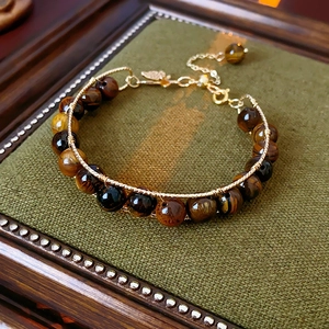 Macro detail of tiger eye stone beads with elegant gold wire wrap and metal clasp