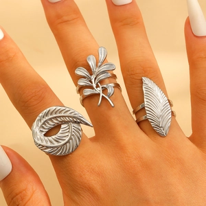 Detailed view of silver stainless steel feather and leaf rings on woman fingers