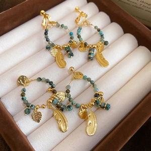 Detail of 14K gold plated bohemian earrings with turquoise beads and feather pendants