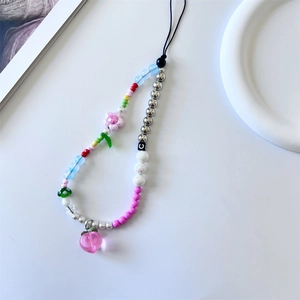 Close-up of pink tulip beads, mushroom and heart charms on a colorful phone strap