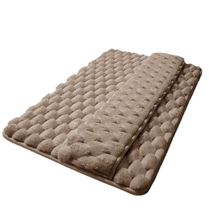 Brown memory foam bath mat with absorbent bubble texture shown folded on white background