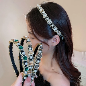 Detail of luxury headbands with emerald crystals and white pearls on a female model