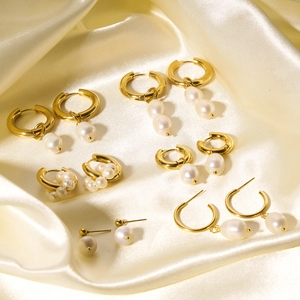 Elegant gold pearl earrings set displayed on beige silk background in soft light