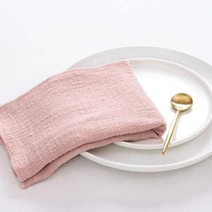 Roze katoenen linnen servet op witte keramische borden met een gouden lepel