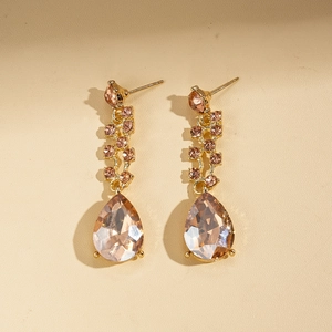 Detail view of gold earrings featuring champagne pear-cut stones and crystal chains
