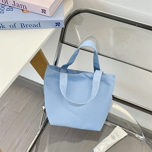 Detail of light blue canvas tote bag on acrylic chair with soft interior lighting