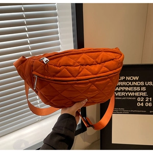Macro detail of vibrant orange quilted crossbody bag with secure zipper closure