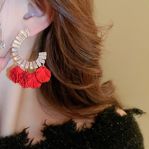 Dettaglio di orecchini in zircone a forma di C con nappe di petali di velluto rosso