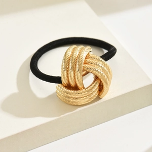 Minimalist elastic hair tie featuring a polished gold metal knot on a studio background