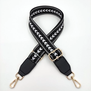 Close-up of black and white geometric woven bag strap with golden metal swivel hooks