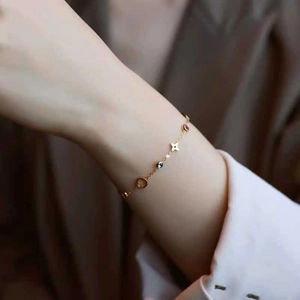Elegant gold titanium steel clover bracelet with pink and blue gemstones on a model's wrist