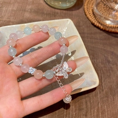 Dettaglio del bracciale con perline rosa e blu con ciondolo a farfalla e catenella regolabile