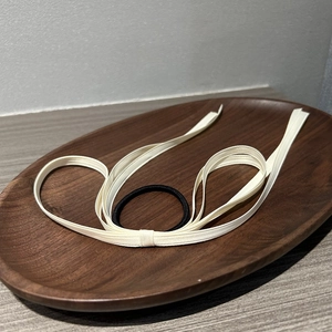 Detail of elegant beige ribbon bow hair tie on dark wooden tray for stylish hair styling